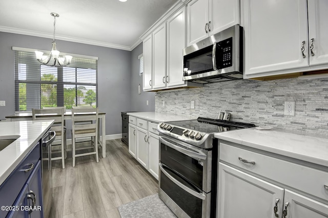 kitchen with ornamental molding, white cabinetry, a notable chandelier, and stainless steel appliances