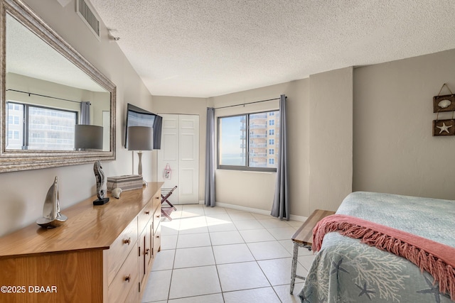 tiled bedroom featuring multiple windows, a textured ceiling, and a closet