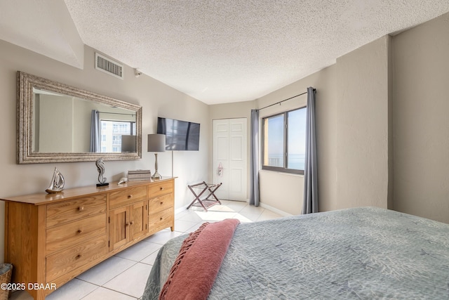 bedroom featuring light tile patterned flooring, a closet, and a textured ceiling