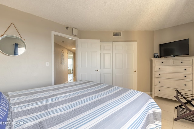 tiled bedroom featuring a textured ceiling and a closet