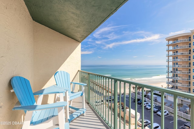 balcony with a water view and a view of the beach