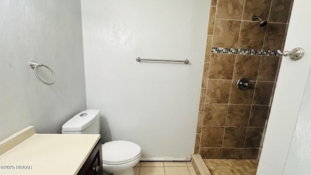 bathroom with tile patterned flooring, toilet, vanity, and tiled shower