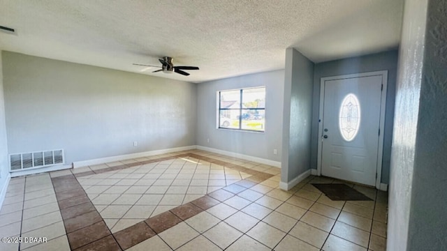 entryway featuring visible vents, baseboards, light tile patterned flooring, a textured ceiling, and a ceiling fan