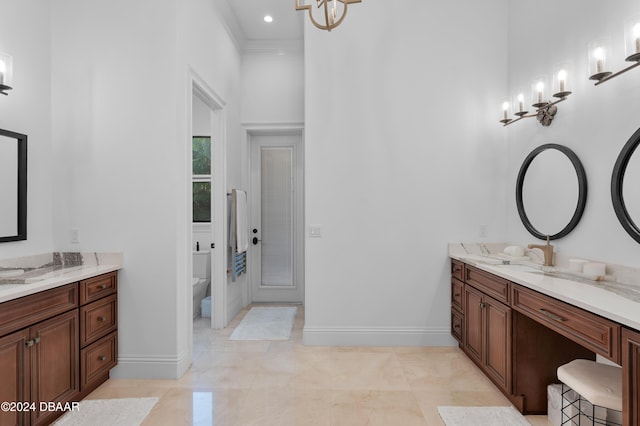 bathroom with ornamental molding, vanity, toilet, and a notable chandelier