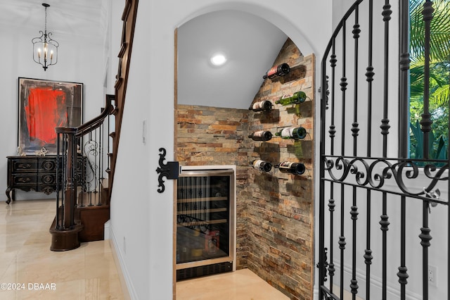 wine area with a notable chandelier, vaulted ceiling, and beverage cooler