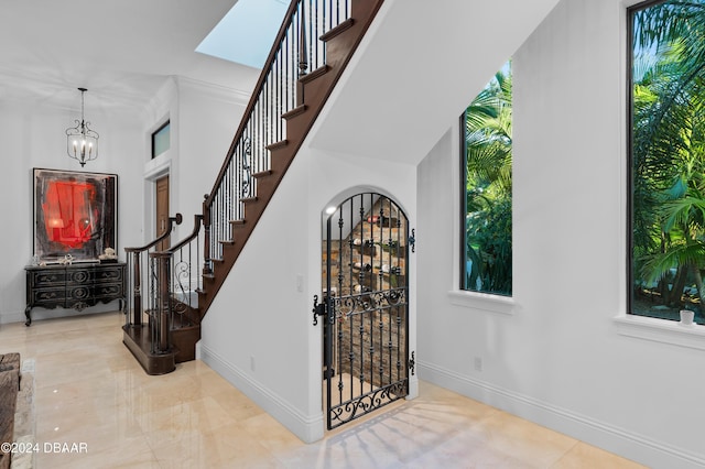 stairs featuring an inviting chandelier, ornamental molding, and a healthy amount of sunlight