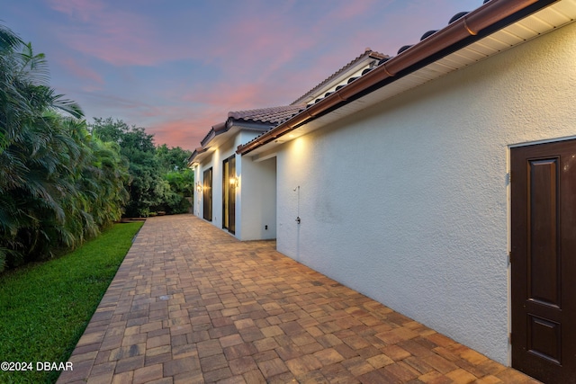 property exterior at dusk with a patio area