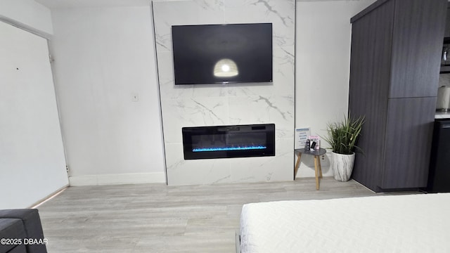 bedroom featuring a high end fireplace and light hardwood / wood-style floors