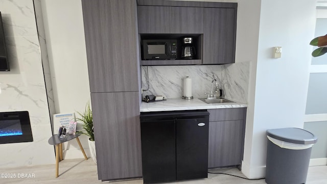 bar featuring tasteful backsplash, light wood-type flooring, and sink