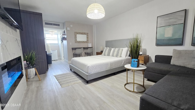 bedroom with a premium fireplace and light hardwood / wood-style flooring