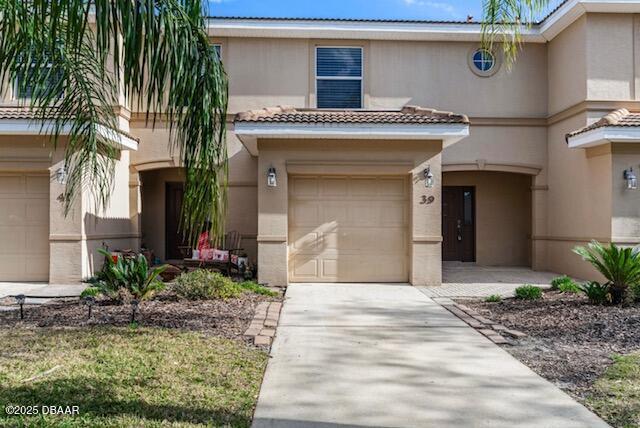 view of front of property with a garage, concrete driveway, a tile roof, and stucco siding