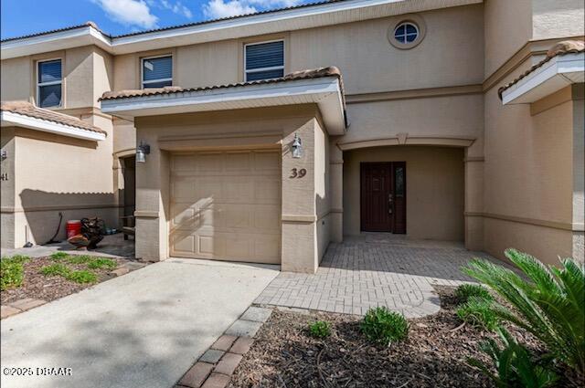 view of front of house with stucco siding, driveway, and an attached garage