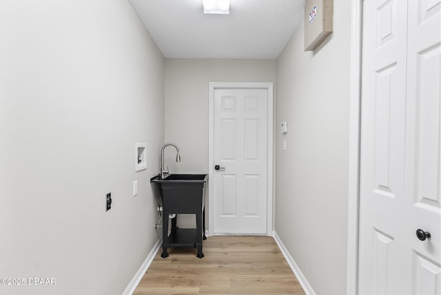 laundry room with light hardwood / wood-style floors, washer hookup, and a textured ceiling