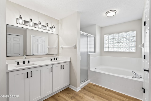 bathroom with a textured ceiling, separate shower and tub, hardwood / wood-style flooring, and vanity