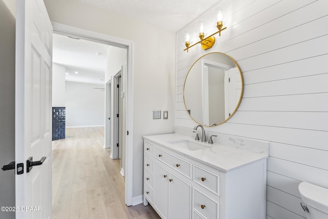 bathroom with toilet, vanity, wood-type flooring, and a textured ceiling