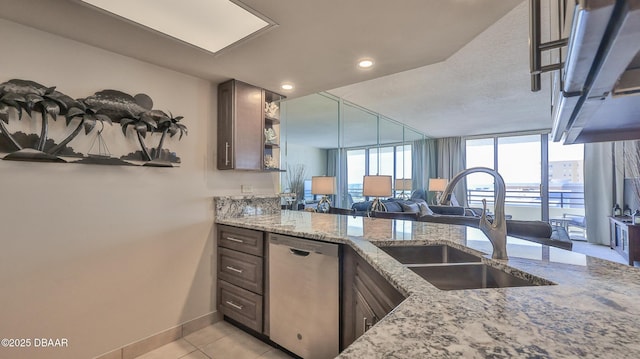 kitchen featuring light stone counters, stainless steel dishwasher, dark brown cabinetry, and sink