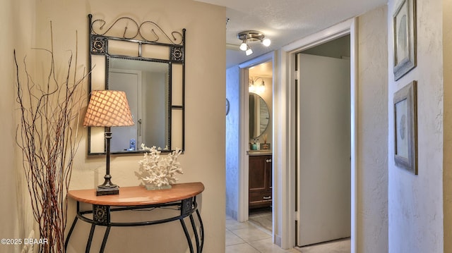 hallway with a textured ceiling and light tile patterned flooring