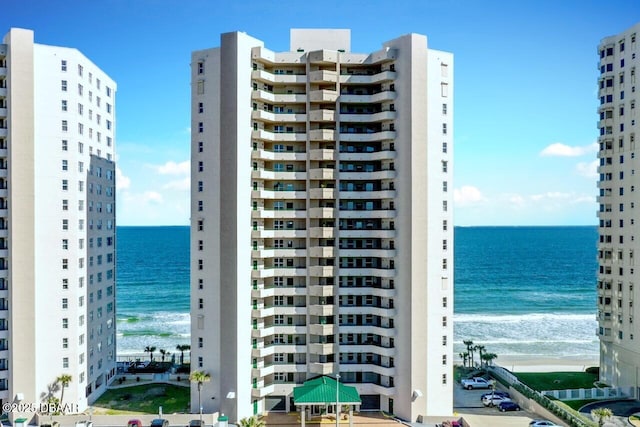 view of building exterior with a beach view and a water view