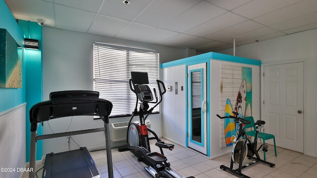 exercise room with a paneled ceiling and light tile patterned floors