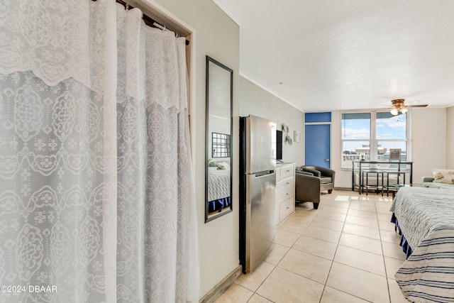 bedroom with light tile patterned flooring, ceiling fan, and stainless steel fridge