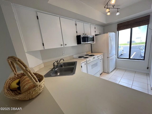 kitchen with white cabinetry, sink, light tile patterned floors, a tray ceiling, and white appliances