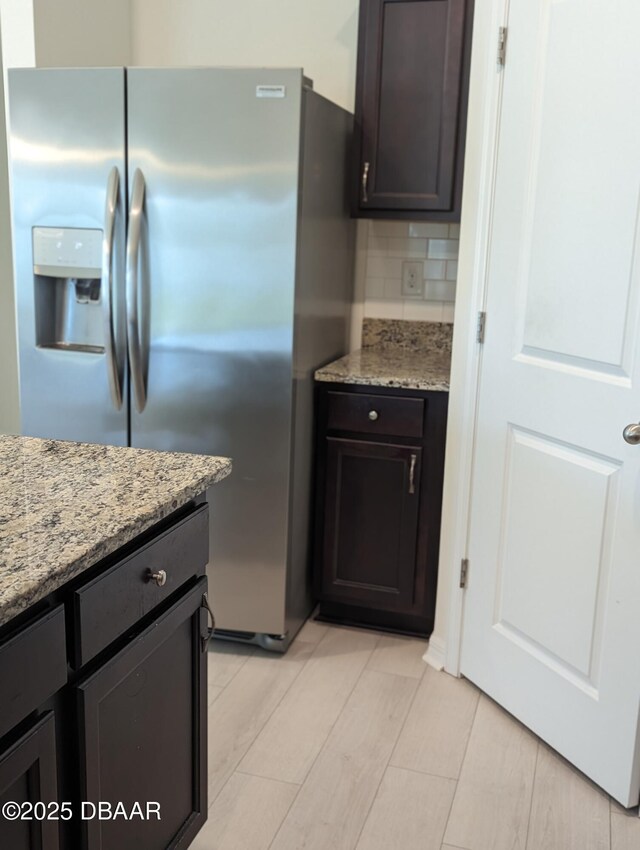 3103 Nova Scotia Way, New Smyrna Beach, FL 32168 - kitchen featuring stainless steel refrigerator with ice dispenser, tasteful backsplash, light stone counters, and dark brown cabinetry