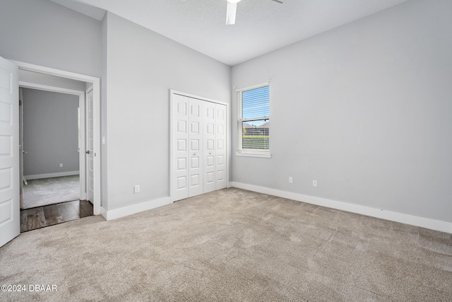 unfurnished bedroom featuring ceiling fan, a textured ceiling, a closet, and light colored carpet