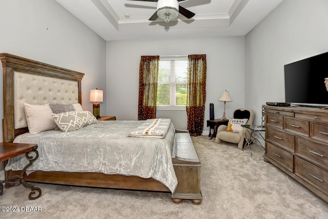 bedroom with light colored carpet, ceiling fan, and a raised ceiling