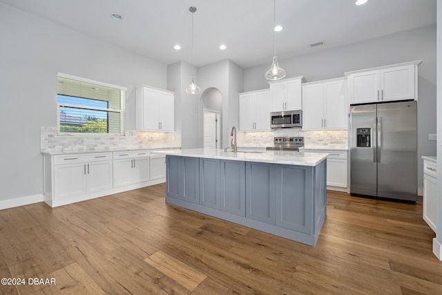 kitchen featuring white cabinetry, appliances with stainless steel finishes, hanging light fixtures, and light hardwood / wood-style flooring