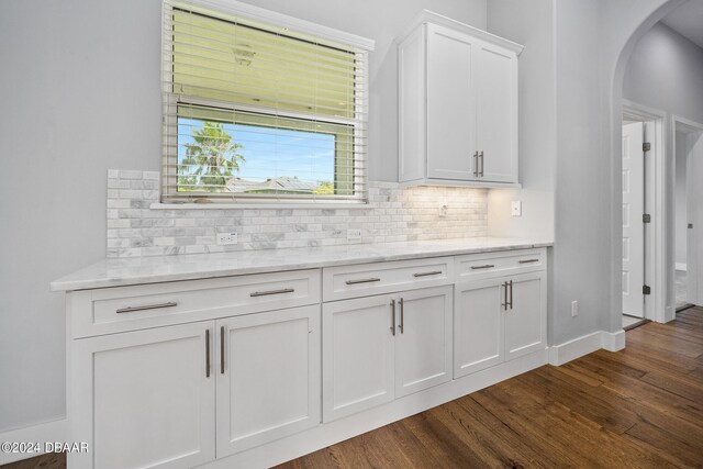 kitchen featuring dark wood-type flooring, backsplash, white cabinetry, and light stone counters