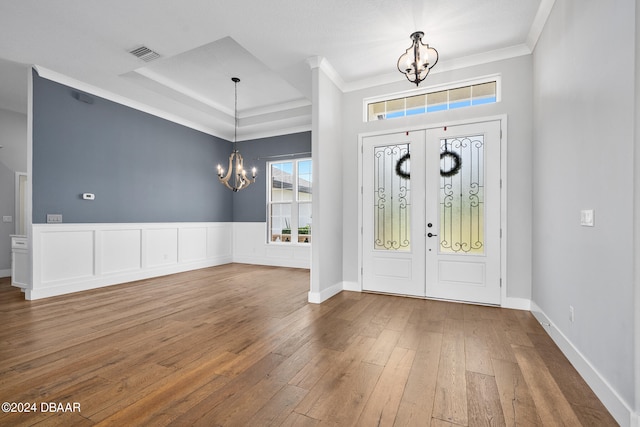 entrance foyer with hardwood / wood-style flooring, an inviting chandelier, french doors, and ornamental molding