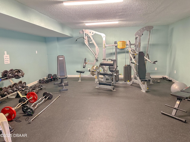 gym featuring a textured ceiling and baseboards