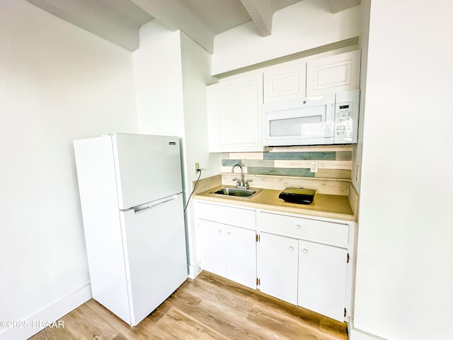 kitchen with light countertops, white appliances, light wood-type flooring, and a sink