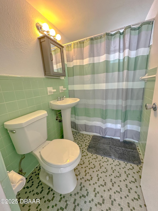 full bathroom with tile walls, curtained shower, toilet, a sink, and tile patterned floors