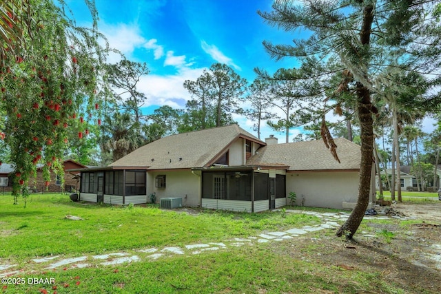 back of property featuring cooling unit, a yard, and a sunroom