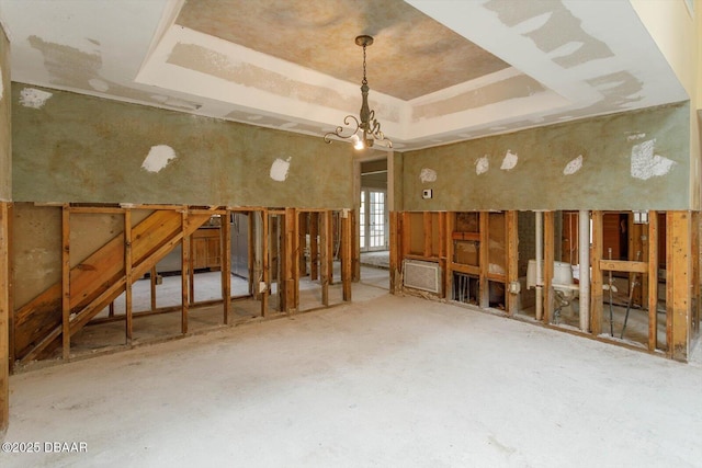 miscellaneous room with a notable chandelier and a raised ceiling