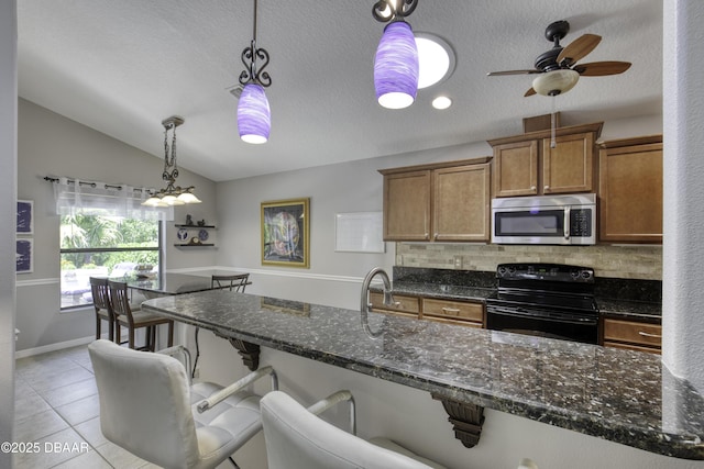 30 Foxfield Look, Ormond Beach, FL 32174 - kitchen featuring decorative backsplash, brown cabinetry, electric range, vaulted ceiling, and stainless steel microwave