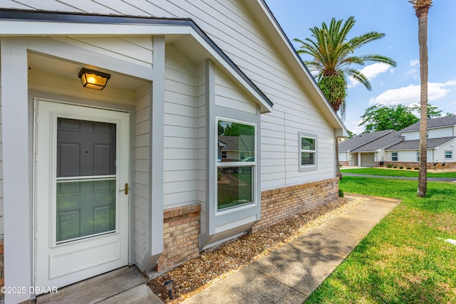 entrance to property featuring brick siding and a yard