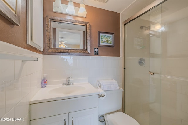 bathroom featuring vanity, a shower with shower door, tile walls, and toilet