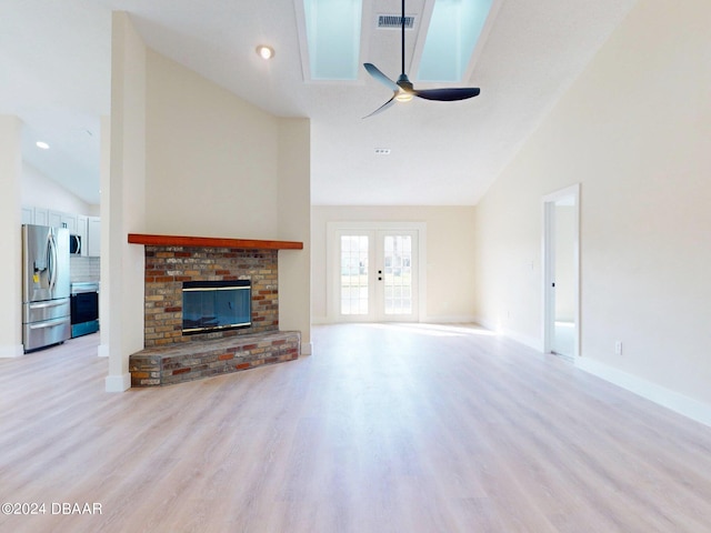 unfurnished living room with ceiling fan, light wood-type flooring, a fireplace, and high vaulted ceiling