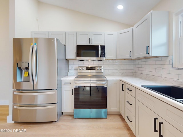804 Soft Pine Ct, New Smyrna Beach, FL 32168 - kitchen with stainless steel appliances, light wood-style floors, lofted ceiling, backsplash, and a sink