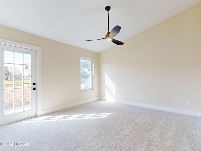 unfurnished room featuring plenty of natural light, ceiling fan, light colored carpet, and vaulted ceiling