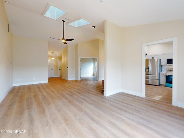 unfurnished living room with ceiling fan, lofted ceiling with skylight, and light wood-type flooring