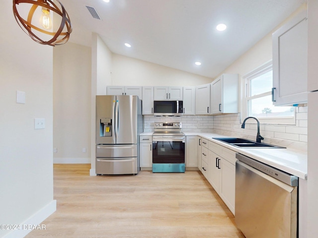 kitchen with sink, vaulted ceiling, light wood-type flooring, white cabinetry, and stainless steel appliances