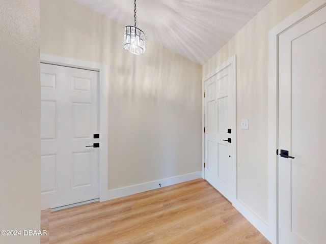 foyer entrance with hardwood / wood-style floors, a textured ceiling, and a notable chandelier