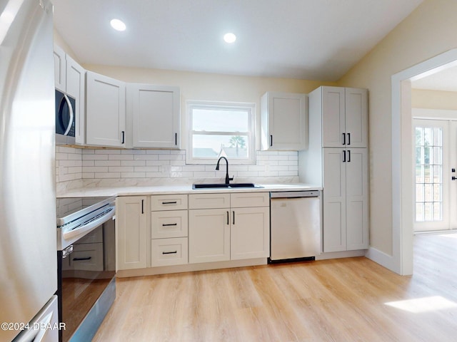 kitchen with decorative backsplash, sink, stainless steel appliances, and light hardwood / wood-style floors