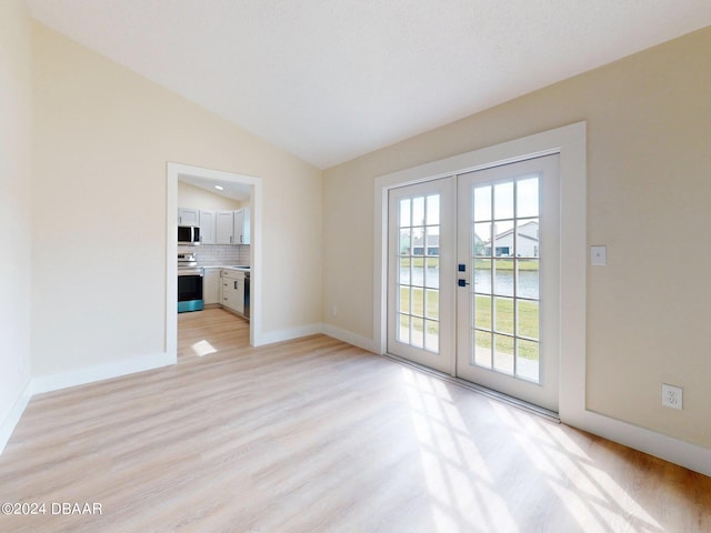 interior space with lofted ceiling, light wood-type flooring, a textured ceiling, and french doors