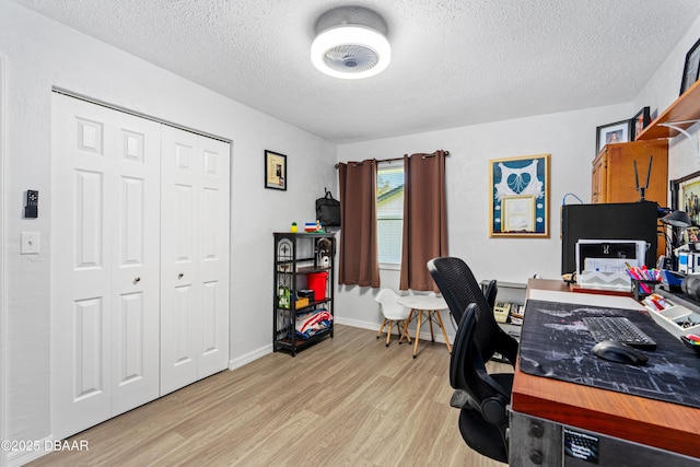 office space featuring light wood-type flooring, a textured ceiling, and baseboards