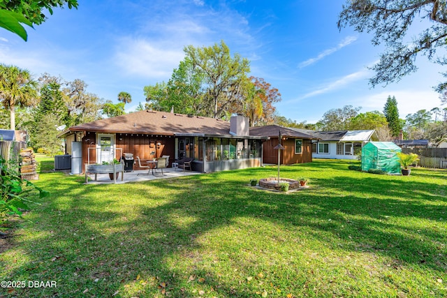 back of property with a sunroom, a chimney, fence, a yard, and a patio area