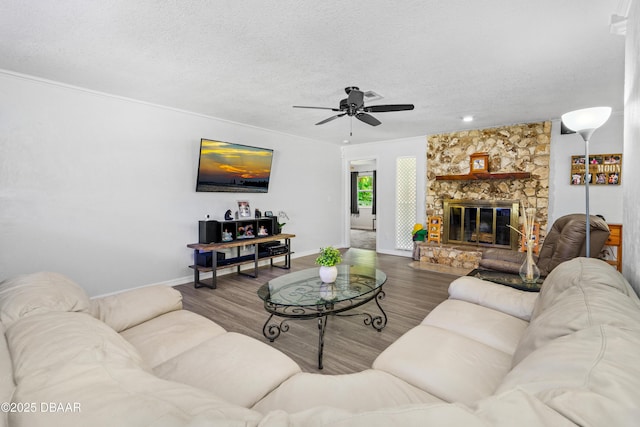 living room with a fireplace, ceiling fan, a textured ceiling, wood finished floors, and baseboards